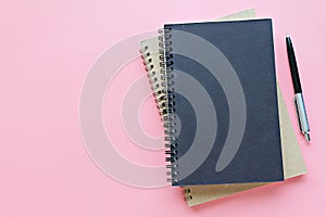 Top view or flat lay of notebooks and pen on pink background, ready for adding or mock up