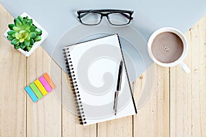 Top view or flat lay of open notebook with blank pages and coffee cup on office table