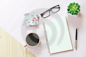 Top view or flat lay of open notebook paper with blank pages, accessories and coffee cup on wooden background