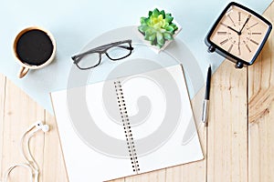 Top view or flat lay of open notebook paper with blank pages, accessories and coffee cup on wooden background, ready for adding or