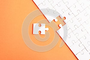 Top view flat lay of paper plain white jigsaw puzzle game texture last pieces for solve and place, studio shot on an orange backgr
