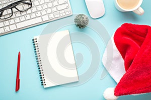Top view flat lay photo of santa claus hat keyboard computer mouse red pen organizer glasses pine toy and cup of hot drinking on