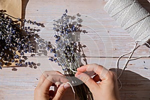 Top view flat lay of process making bouquets of dried lavender flowers. Cotton rope, scissors. Female do homemade herbs