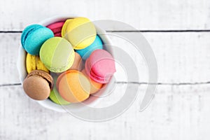 Top view flat lay Vibrant colorful macarons in plate on white wooden table