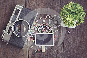 top view flat lay vintage camera, compass, plant and signage on wooden background