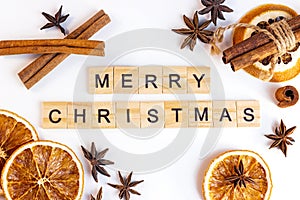 Top view flat lay of wooden Merry Christmas text with spices for traditional beverages: cinnamon sticks, anise stars, dry orange