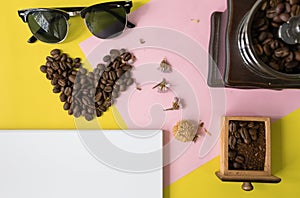 Top view flat layer heart smile icon shape ,sun glasses, vintage wooden coffee grinder and blank book for copy space on two tone