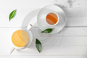 top view or flatlay with herbal tea in a cup and teapot on white wooden background, teatime ceremony, traditional