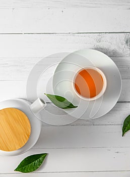 top view or flatlay with herbal tea in a cup and teapot on white wooden background, teatime ceremony, traditional