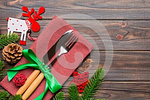 Top view of flatware tied up with ribbon on napkin on wooden background. Christmas decorations and reindeer with empty space for