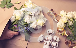 Top view of the florist's table - the process of packaging the composition of flowers in craft paper