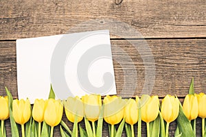 Top view of the flowers arranged on boards. Floating frame. Blank white envelope tucked under the tulips.