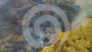 Top view and flying over field with line of fire with red pickup car. Epic video shooting, smoke clouds, spread of