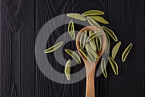 Top view of foglie spinach pasta on black wooden table with spoon