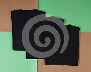 Top view of folded black t-shirt  with colored background  copy space  flat lay.