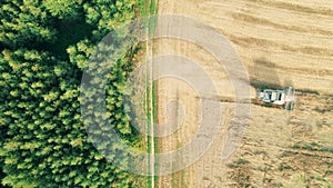 Top view of a forest and a field with crops getting reaped