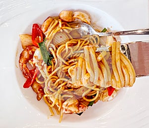 Top view of Fork with just Spaghetti around on Fusion prawns and squids Stir Fried Chili Paste spaghetti in white ceramic plate