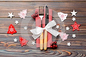 Top view of fork and knife on napkin on wooden background. Different christmas decorations and toys. Close up of New Year dinner