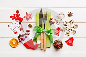 Top view of fork and knife on napkin on wooden background. Different christmas decorations and toys. New Year dinner concept with