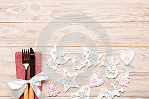 Top view of fork and knife on napkin on wooden background. Different christmas decorations and toys. New Year dinner concept with