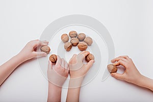 top view four child hand with many walnuts isolated on white background,