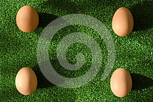 Top view of four eggs on green grass background, with copy space
