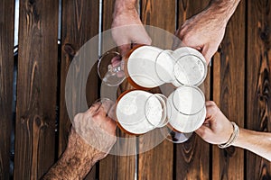 Top view of four hands with beers cheering and having fun together