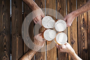 Top view of four hands with beers cheering and having fun together