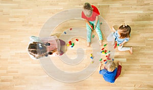 Top view of four kids constructing of wooden blocks