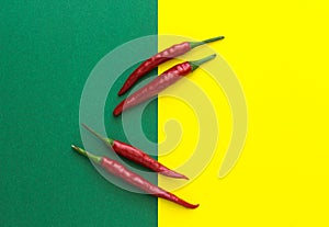 Top view, four red chili peppers on a yellow-green background