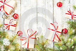 Top view on frame from Christmas decorations, gift boxes, fir branches on the wooden background decorated with snow