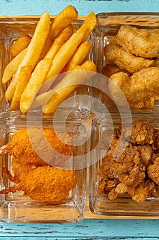 french fries and deep fried shrimps and chicken nuggets and popcorn chicken vertical composition