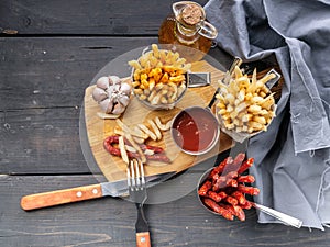 Top view french fries with tomato sauce and a portion of smoked sausages on a rustic background. Tasty Fast Food Snacks. Fork,