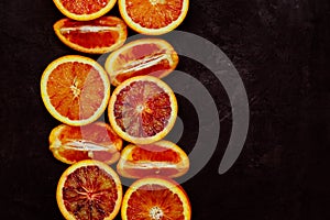 Top view of fresh blood orange halves and quaters on black background with copy space. Toned image