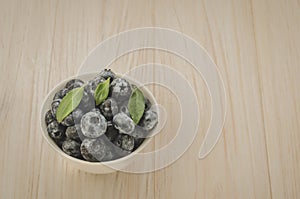 top view on fresh blueberries in white bowl on a wooden background/top view on fresh blueberries in white bowl on a wooden