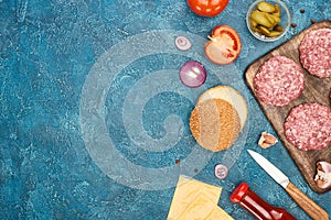 Top view of fresh cheeseburger ingredients on blue textured surface