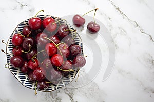 Top view of fresh cherries on bowl on marble background with copy space