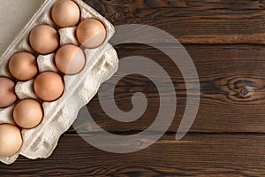 Top view of fresh eggs on paper tray on dark backdrop