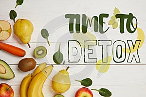 top view of fresh fruits and spinach leaves on white wooden background with copy space, time to detox inscription