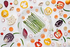 top view of fresh green asparagus on plate and fresh sliced vegetables