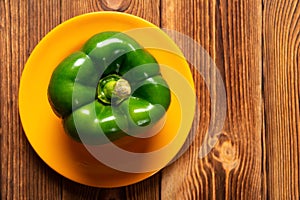 Fresh green bell pepper with drips on wood table