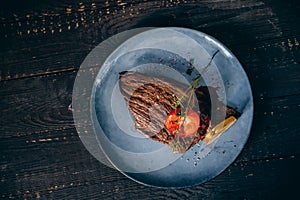 Top view Fresh grilled meat steak with pear and tomato decoration. Black background
