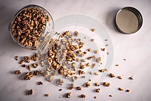 Top view of fresh homemade healthy granola in a glass jar on a breakfast white marble table