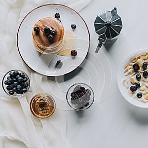 top view of fresh homemade pancakes with honey and berries coffee pot and muesli with milk