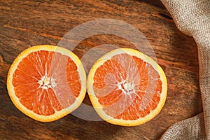 Top view of fresh orange fruit half slices on wooden board background