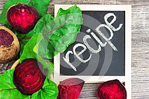 Top view at fresh organic beets with green leaves with recipe on wooden rustic background. Close up view