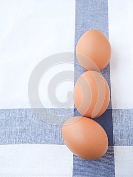 Top view fresh organic eggs put on a white dishcloth with blue straight stripes.