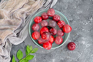 Top view of fresh organic ripe plums in ceramic bowl decorated with grey gauze fabric, leafs, copy space. Flat lay.