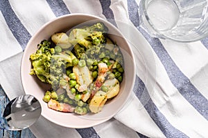 Top view on fresh prepared broccoli with gnocchi in bowl on the table - homemade healthy food in bright light with copy space