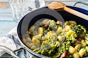 Top view on fresh prepared broccoli with gnocchi in casserole dish on the wooden table - homemade healthy food in bright light